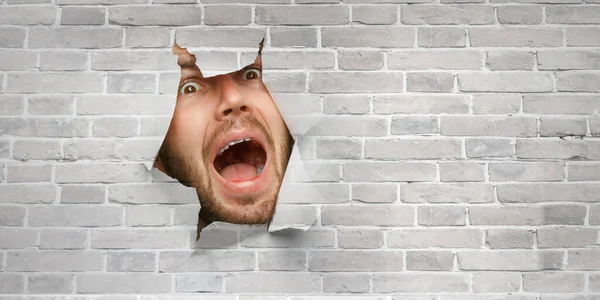 Manligt ansikte genom hålet i papper — Stockfoto