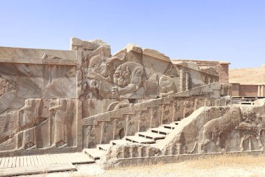 İran 'ın antik Persepolis şehrinin duvarında ünlü bas-rahatlama hareketi. Aslan boğaya saldırır ve onu ısırır (toprağın doğurganlığını ve mevsimlerin değişimini sembolize eder). UNESCO dünya mirası sahası