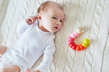 Yeni doğan bebek kız renkli oyuncakla oynamak. Bebekler için geliştirme oyunları