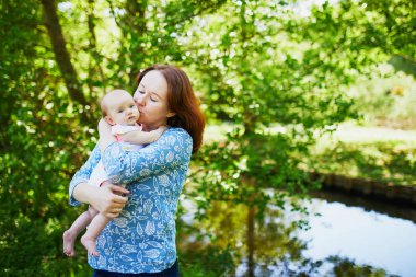 Annesi 2 aylık bebeğini kucağına alıp öpüyor.