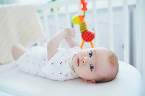 赤ちゃんの女の子は 両親のベッドに接続されている共同ベッドに横たわっておもちゃと遊ぶ — ストック写真