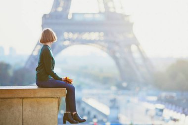 Güzel genç Fransız kadın renkli sonbahar grup ile Paris'te Eyfel Kulesinin yakınında bir sonbahar gününde bırakır