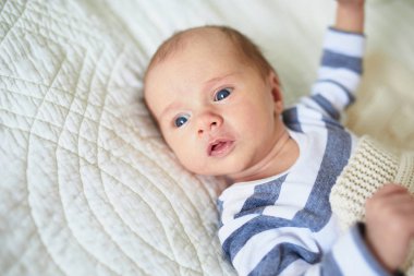 Sevimli bir kız bebek bebek odasında yatakta yatıyor.