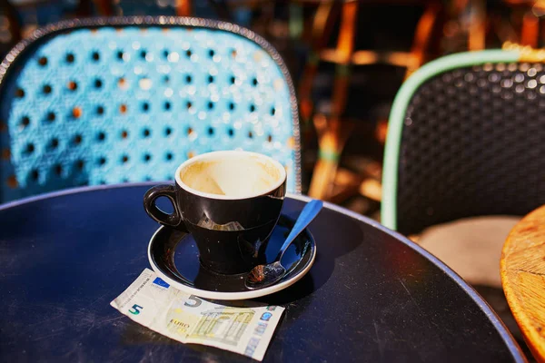 空杯黑咖啡和5欧元钞票在巴黎的一个户外咖啡馆的桌子上 — 图库照片