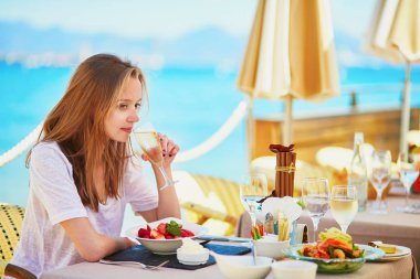 Şampanya içmek ve meyve onun tatil ba deniz sırasında beach restoranda yemek güzel genç kadın