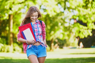 Kitaplar ve klasörlerle kampüsünde bir güneşli yaz veya sonbahar günü neşeli genç öğrenci. Geri okul kavramı