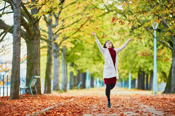 美丽的年轻女子在巴黎漫步在公园的一个明亮的秋季一天 扔树叶 法国秋季旅游与度假 — 图库照片