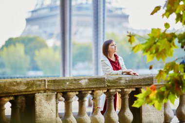 Bir-Hakeim Köprüsü'nde Güz veya bahar günü Eyfel Kulesi manzaralı güzel genç kadın Paris'te. Turizm ve tatil Fransa
