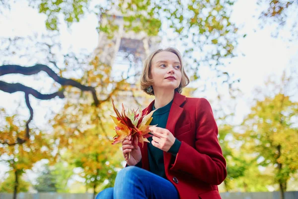 美丽的年轻法国妇女与一串五颜六色的秋天叶子在巴黎埃菲尔铁塔附近在秋天天 — 图库照片