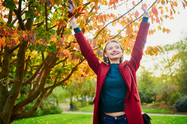 カラフルな秋の束と美しい若い女性の葉秋の日に公園を歩いて — ストック写真