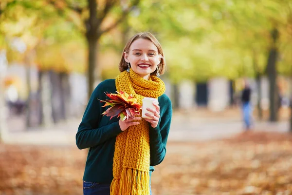 愉快的小女孩在黄色围巾与咖啡去漫步在秋天公园在一个明亮的秋天天 — 图库照片