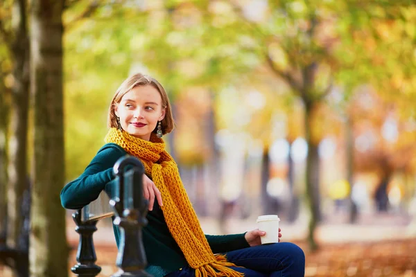愉快的小女孩在黄色围巾与咖啡去漫步在秋天公园在一个明亮的秋天天 — 图库照片