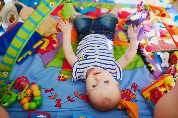 小女孩有许多五彩缤纷的玩具 小孩躺在垫子上 幼儿保育室 — 图库照片