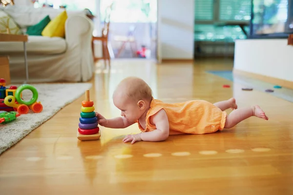 小女孩玩堆叠戒指玩具 小孩躺在地板上拿着玩具 幼儿保育室 — 图库照片