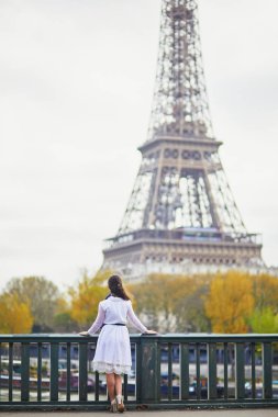 Fransa'nın Paris, Eyfel Kulesi yakınındaki beyaz elbiseli mutlu genç kadın