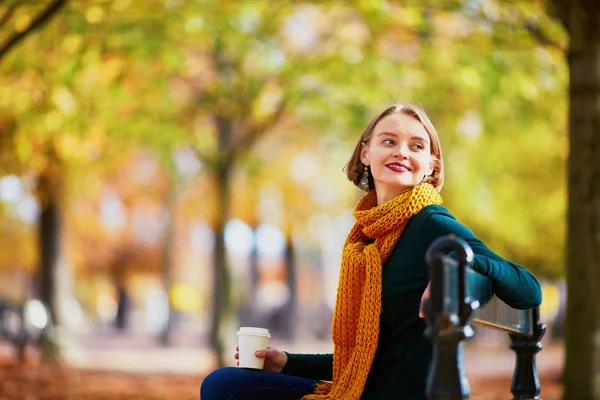 明るい秋の日秋の公園で散歩に出掛けるにコーヒーと黄色のスカーフで幸せな若い女の子 — ストック写真
