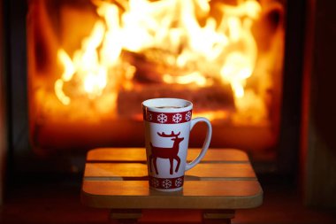 Bir fincan sıcak çikolata ve şekerleme yakın birçok mum ile şömine. Rahat romantik Noel akşam