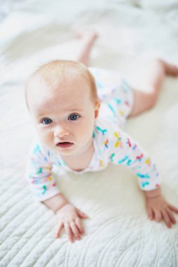 Bebek emeklemeyi öğreniyor. Küçük çocuk vücudunu kollarıyla kaldırıyor. Güneşli kreşte küçük bir çocuk.