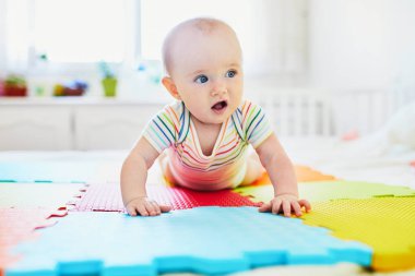 Bebek emeklemeyi öğreniyor. Küçük çocuk vücudunu kollarıyla kaldırıyor. Güneşli kreşte küçük bir çocuk.