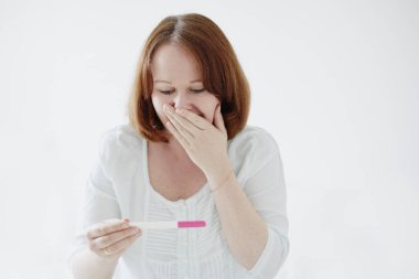 Mutlu genç kadın pozitif gebelik şerit test arıyor. Gebelik, doğurganlık ve annelik kavramı