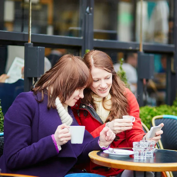 Две Девушки Кафе Открытом Воздухе Пьют Кофе Пользуются Мобильным Телефоном — стоковое фото