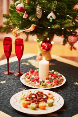 Tablo Noel yemeği lezzetli meze ve şampanya ile ayarla. Arka planda bir şekilde dekore edilmiş Noel ağacı