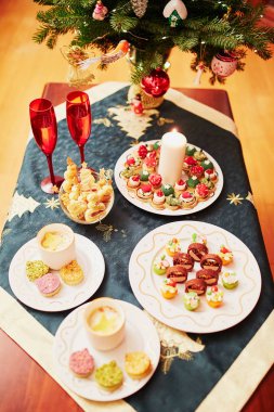 Tablo Noel yemeği lezzetli meze ve şampanya ile ayarla. Arka planda bir şekilde dekore edilmiş Noel ağacı