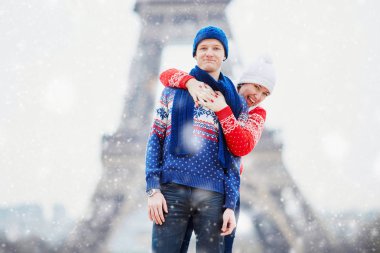 Mutlu çift yağan kar altında bir kış gününde Eyfel Kulesinin yakınında. Paris gezisi sırasında sezon tatil