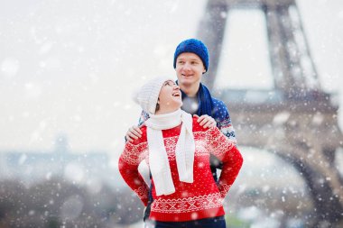 Mutlu çift yağan kar altında bir kış gününde Eyfel Kulesinin yakınında. Paris gezisi sırasında sezon tatil