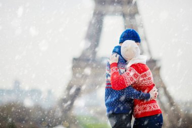 Mutlu çift yağan kar altında bir kış gününde Eyfel Kulesinin yakınında. Paris gezisi sırasında sezon tatil
