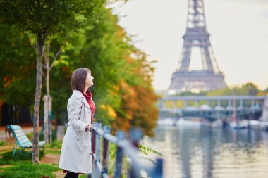 Güzel genç kadın Paris'te Eyfel Kulesi ve Seine bir parlak sonbahar gününde bakarak. Turizm ve tatil Fransa sonbahar sezon