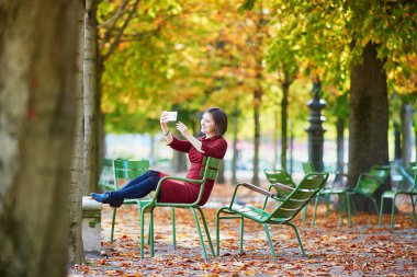 Selfie cep telefonu ile alarak güzel genç kadın Tuileries garden Paris bir parlak sonbahar gününde. Turizm ve tatil Fransa sonbahar sezon