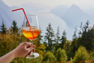 Kokteyl aperol spritz doğal manzaralı cam Monte Bre Lugano, Ticino, İsviçre üzerinden lake Lugano tutan kadın
