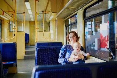 Kadın penceresine bakarak tren, küçük kız. Anne ile bebek demiryolu toplu taşıma araçları ile seyahat. Çocuklarla seyahat