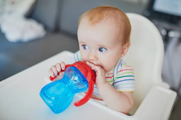 小さな赤ちゃんの女の子座っている高い椅子で自宅やレストランや飲み水からシッピーカップ — ストック写真