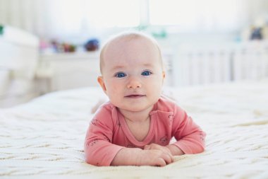 Karnı yatakta yatan kız bebek. Pembe elbise mutlu sağlıklı küçük çocuk. Güneşli kreş çocuk