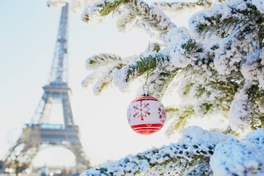 Noel ağacı karla kaplı ve Fransa'nın Paris, Eyfel Kulesi yakınındaki kırmızı topu ile dekore edilmiş