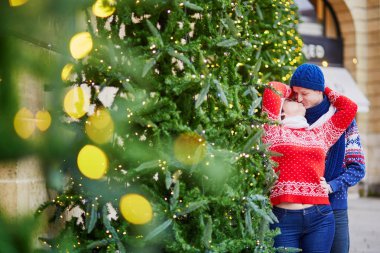 Mutlu çift renkli kazak Paris bir sokakta yürümek içinde Noel için dekore edilmiştir.