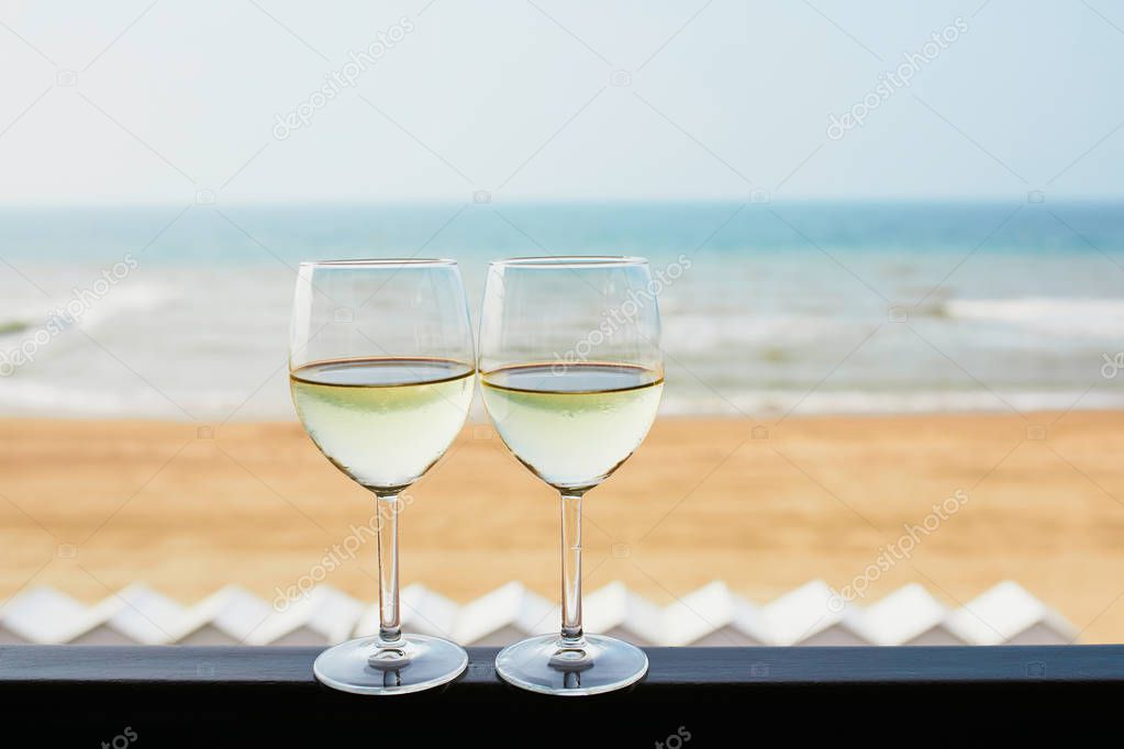 Two glasses of white wine with Atlantic coast beach in background. Normandy, France