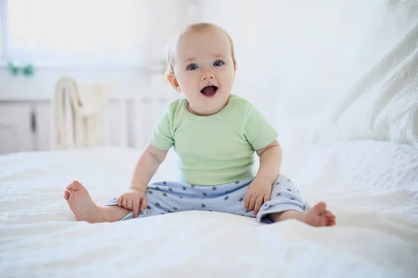 赤ちゃんの女の子ベッドの上に座って笑っている 自宅で幸せな健康な小さな子供 日当たりの良い保育園の幼児 — ストック写真