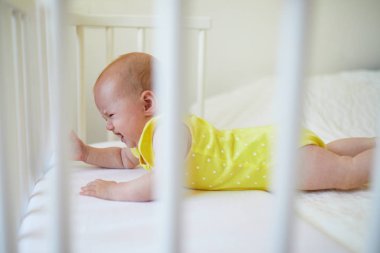 Co uyuyan beşiğinde yatan bebek kız anne babamın yatak ve ağlıyor bağlı. Küçük çocuk karyolası gün kestirmek isteyen değil. Güneşli kreş çocuk