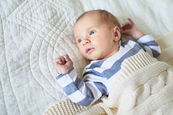 Очаровательная малышка лежит на кровати в детской
