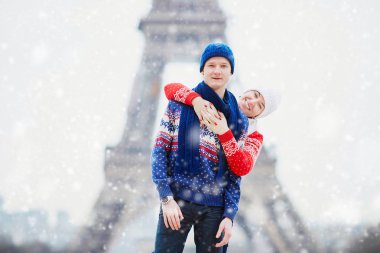 Mutlu çift yağan kar altında bir kış gününde Eyfel Kulesinin yakınında. Paris gezisi sırasında sezon tatil
