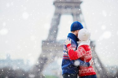 Mutlu çift yağan kar altında bir kış gününde Eyfel Kulesinin yakınında. Paris gezisi sırasında sezon tatil