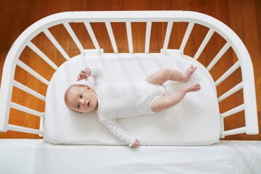 Anne babamın yatağa bağlı eş uyuyan beşik bebek kız. Küçük çocuk karyolası uyku bir gün geçiriyorum. Güneşli kreş çocuk