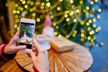 Ona kahve fincanı ve Noel hediyesi mevsimlik tatil için dekore edilmiş kafede fotoğraf pf alarak kadın
