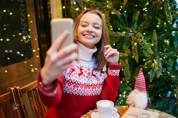 Jovencita Alegre Suéter Vacaciones Cafetería Decorada Para Navidad Haciendo Selfie —  Fotos de Stock
