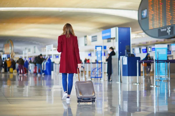 年轻女子在国际机场走带着行李 准备她的航班 — 图库照片