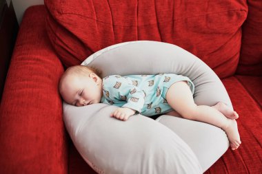 Evde emzirme yastığında uyuyan tatlı bir kız bebek.