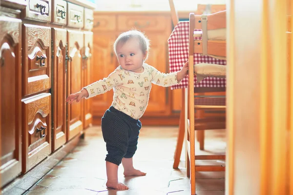 Pikkutyttö Seisoo Lattialla Keittiössä Pitää Kiinni Huonekaluista Pieni Lapsi Retkellä — kuvapankkivalokuva